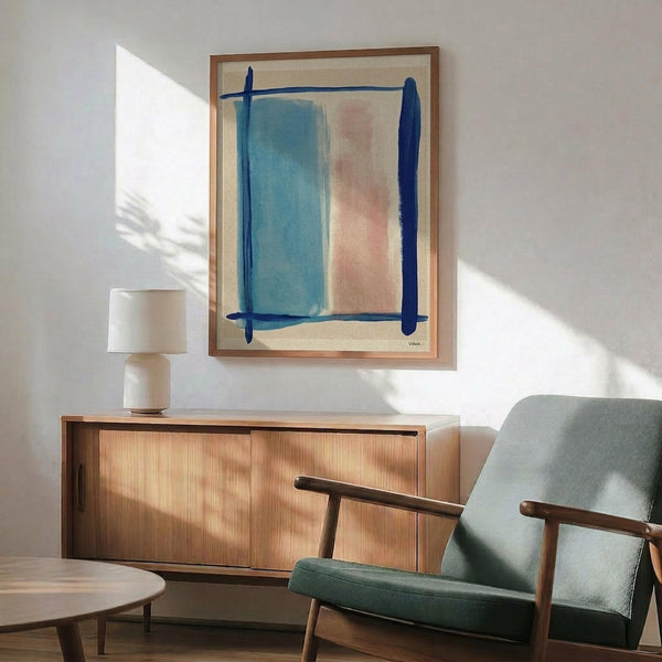 May include: Abstract artwork with blue and coral pink brushstrokes framed in natural wood, displayed above a mid-century modern walnut credenza with a ceramic table lamp. Sage green upholstered armchair with wooden frame sits nearby on hardwood floors. Soft natural light creates shadows on white wall in minimalist living room setting.