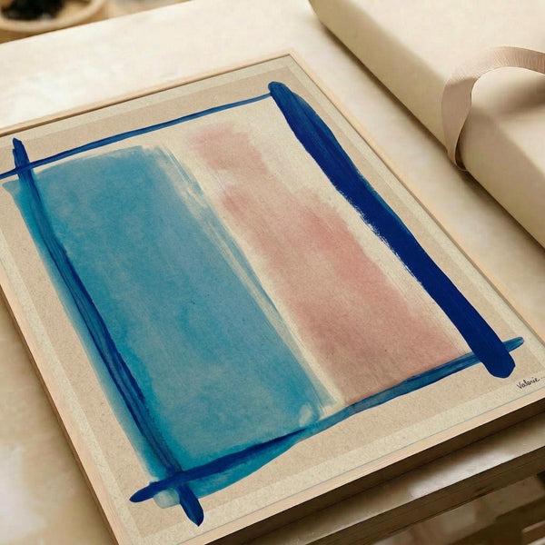 Abstract minimalist artwork featuring soft blue and pink rectangular color blocks with bold navy blue brushstrokes forming a loose frame around the composition. The piece has a watercolor-like texture with gentle color gradients and is displayed on cream-colored paper within an open art portfolio or sketchbook, surrounded by neutral-toned materials and ribbon.