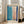 May include: Abstract art print in light wood frame leaning against white wall next to beige sofa. Artwork features soft blue and pink rectangular color blocks with bold navy blue brushstroke borders on cream background. Modern minimalist living room with large windows and natural lighting.