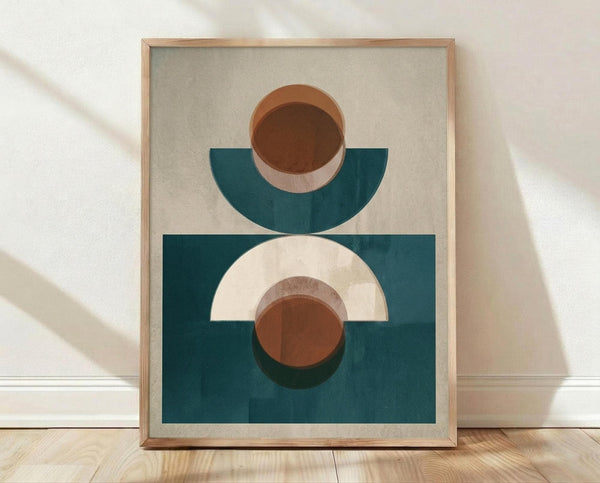 May include: Framed geometric abstract art print leaning against white textured wall on light wood floor. The artwork features layered semi-circles and circles in terracotta brown, cream, and teal blue tones on a neutral beige background, displayed in a natural wood frame. Soft natural lighting creates gentle shadows across the scene.