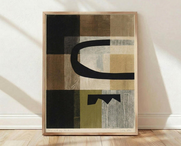 May include: Modern abstract art print in light wood frame leaning against white wall on wooden floor. Artwork features geometric shapes in muted earth tones - black, brown, olive green, cream, and gray - with curved and angular black elements creating dynamic composition. Soft natural lighting casts shadows across textured fabric background.