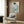 May include: Framed Asian-inspired artwork showing a woman in white and blue striped kimono with green floral pattern, displayed above a beige upholstered armchair with geometric pillow in modern living room with wood paneling, floor lamp, and side table