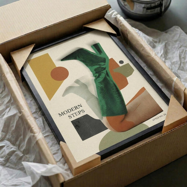 May include: Abstract art print with geometric shapes in green, orange, yellow, and cream tones, featuring curved and angular forms. Black frame displayed in cardboard shipping box with wooden frame corners and white tissue paper packaging. Print shows "MODERN STEPS" text and "STYLE NO. 24" in corner.