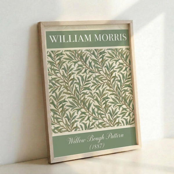 May include: Framed art print featuring William Morris's Willow Bough pattern from 1887, displayed in light wood frame against white wall. Design shows intricate green and cream botanical pattern with flowing willow branches and leaves. Green header and footer bands contain white text identifying the artist and pattern details.