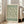 May include: Framed botanical poster with green willow branch pattern on cream background, displayed in bright living room with beige sofa, wooden floors, and large windows. Light wood frame, approximately 2-3 feet tall, leaning against white wall with natural sunlight streaming across the space.