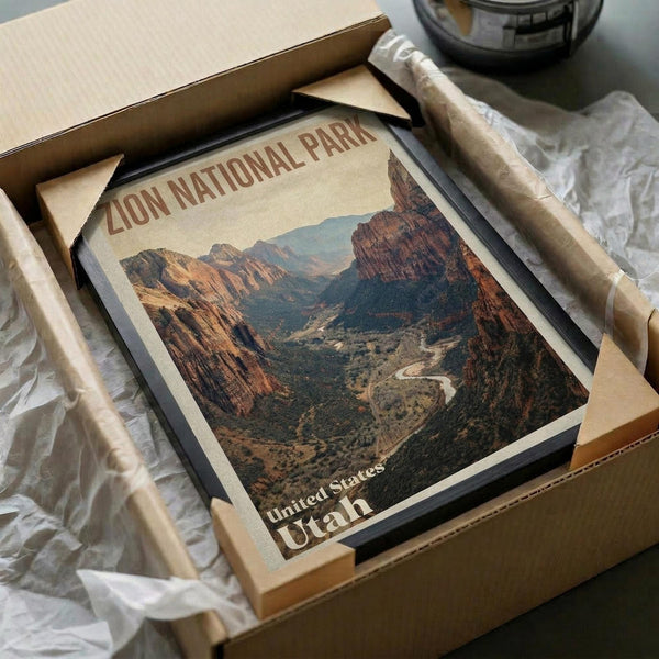 May include: Vintage-style poster print of Zion National Park featuring dramatic red rock canyon landscape with winding river through valley floor. Print shows warm desert tones of orange, red, and brown rock formations against blue sky. Displayed in dark frame, carefully packaged in cardboard box with protective tissue paper wrapping.
