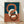 May include: Framed abstract art print featuring three interlocking oval rings in terracotta orange, cream, and dark brown against a split background of teal blue and dusty rose. The wooden frame sits on light hardwood flooring against white fabric backdrop with soft natural lighting creating gentle shadows.
