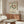 May include: Vintage-style Henri Matisse exhibition poster featuring dancing figures in green, orange and brown tones, displayed above a mid-century modern walnut credenza with sliding doors. Scene includes white curved chair, brass floor lamp, round glass coffee table, and modern table lamp. Poster shows text in English and Japanese for Musée d'Art Moderne de Paris exhibition titled La Danse - Line & Rhythm.