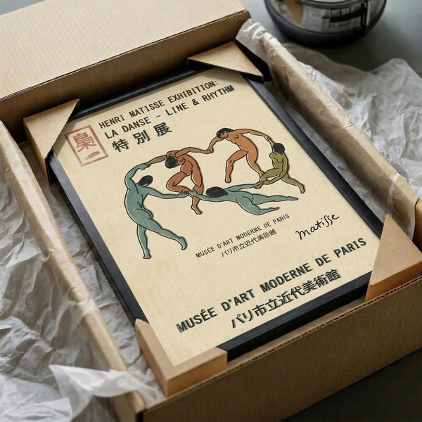May include: Framed vintage-style exhibition poster featuring dancing figures in green, brown and cream colors, displayed in black frame inside cardboard shipping box with protective wrapping materials on white surface