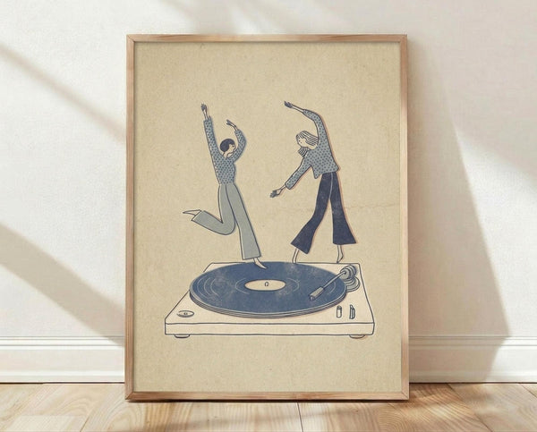 May include: Framed poster print leaning against white wall on light wood floor. Cream-colored artwork shows two people in blue patterned clothing dancing on top of a turntable with vinyl record. Figures have arms raised in joyful dance poses. Simple line art style in blue tones on beige background. Natural wood frame. Soft natural lighting creates shadows on wall.