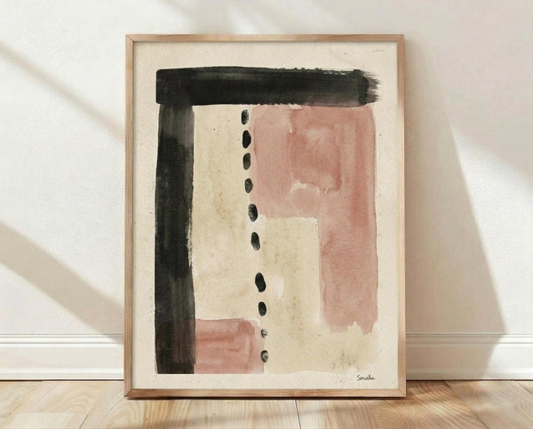 May include: Framed abstract watercolor artwork leaning against white wall on light wood floor. The piece features soft pink rectangular shapes, bold black brushstrokes forming an L-shape, and a vertical line of small black dots on cream textured paper. Natural light casts diagonal shadows across the scene. Light wood frame complements the minimal, modern aesthetic.