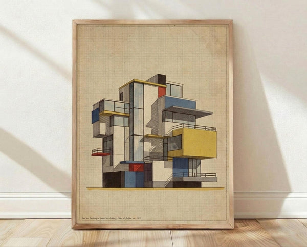 May include: Framed modernist architectural drawing showing an abstract geometric building composition with colorful rectangular modules in yellow, blue, red, and gray stacked at various angles. The artwork features clean lines and appears to be a vintage mid-century design study rendered on textured beige paper, displayed in a natural wood frame against white walls on light wooden flooring with soft natural lighting.