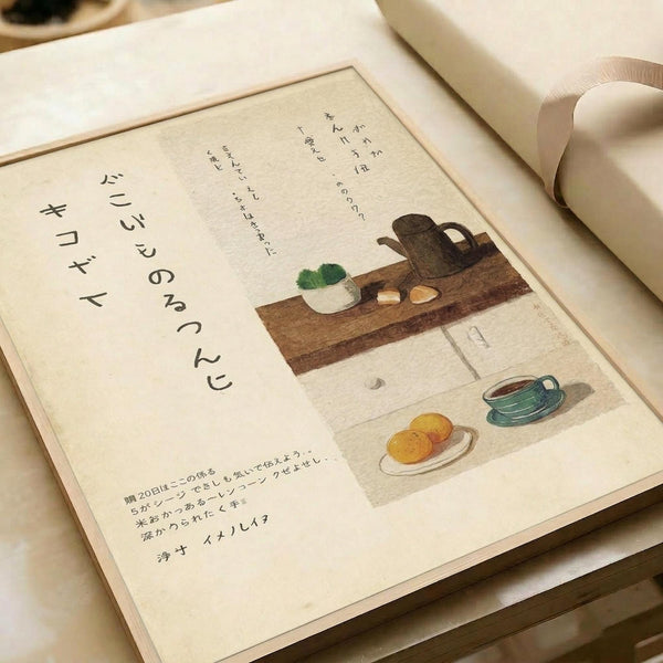 May include: A framed poster with Japanese calligraphy and watercolor illustrations showing kitchen items on wooden surfaces - a dark teapot, white bowl with green plant, oranges on a plate, and a teal cup. The artwork has cream background with black vertical text on the left side and smaller text at bottom. The frame appears light wood-toned, displayed on white bedding with soft natural lighting.
