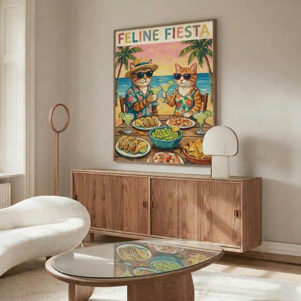 May include: Colorful poster featuring two cats in sunglasses and Hawaiian shirts sitting at a beach table with tacos, margaritas, and guacamole. Palm trees and ocean visible in background with "FELINE FIESTA" text at top. Displayed above a mid-century modern walnut credenza in a minimalist living room with white curved chair and glass coffee table.