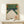 May include: Framed vintage Japanese art print depicting a bowling alley interior with white pins, green lanes, and red circular lights. The artwork features Japanese characters in orange text and has a woodblock print aesthetic. Displayed on a light wood console table with a small wrapped gift box beside it against a cream wall.