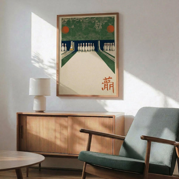 May include: Framed vintage Japanese bowling alley artwork displayed above a wood credenza in a mid-century modern living room setting. The poster features green and cream tones with bowling pins and red circular elements, plus orange Japanese characters. A mint green upholstered armchair with wooden frame sits nearby, along with a small white table lamp and round coffee table, all bathed in natural window light.