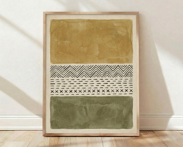 May include: Abstract art print in light wood frame leaning against white wall on wooden floor. Artwork features horizontal bands of ochre yellow and olive green watercolor washes separated by black geometric patterns including chevrons, dashes, and crosses on cream background.