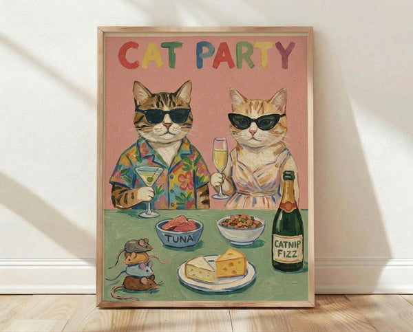 May include: Framed poster print leaning against white wall on light wood floor. Pink background with colorful "CAT PARTY" text. Two cats in sunglasses - tabby in tropical shirt holding martini, orange cat in striped dress with champagne flute. Green table displays tuna bowl, kibble bowl, cheese plate, catnip fizz bottle, and toy mice. Light wood frame with natural lighting and soft shadows.