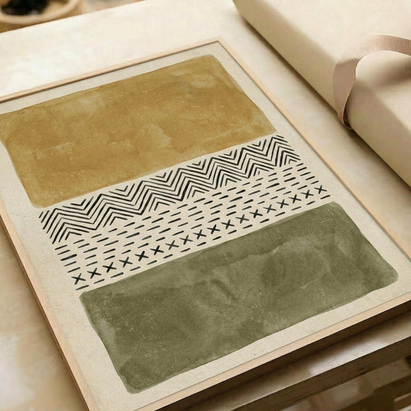 Abstract geometric artwork featuring three horizontal bands - warm ochre yellow at top, sage green at bottom, and white center section with black tribal patterns including chevrons, crosses, and linear designs. The print sits on neutral paper with soft natural lighting, alongside rolled paper tubes in a minimalist workspace setting.