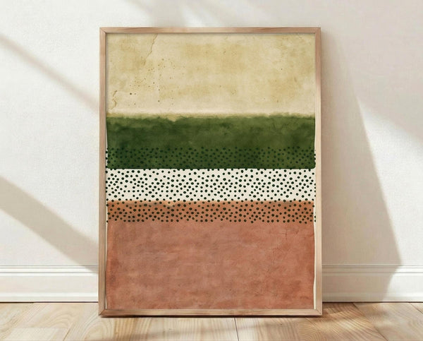 May include: Framed abstract art print with horizontal color bands in cream, forest green, white, and terracotta pink, featuring black polka dot patterns in the middle sections. Wooden frame sits on light hardwood flooring against white walls with natural window light casting soft shadows.