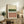 May include: Abstract art print with horizontal bands in cream, forest green, white with black dots, and terracotta pink, displayed in light wood frame on rustic wooden sideboard alongside fern plant, books, and ceramic vase in cozy living room setting with leather armchair