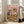May include: Framed poster displayed in bright living room with beige couch and white walls. Artwork shows tabby cat wearing chef's hat and golden retriever in sunglasses sitting at messy dinner table covered in spaghetti, wine bottles, and scattered dishes. Colorful lettering reads "PASTA DISASTER" against pink background in vintage illustration style.