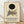 May include: Framed exhibition poster leaning against white wall on light wooden floor. Features abstract geometric composition with black circle, blue triangle, yellow rectangles, gray shapes, and intersecting red and white lines on cream background. Bold "KANDINSKY" text below with Tate Britain exhibition details. Natural wood frame with soft lighting and fabric shadows visible.