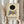 May include: Person in cream sweater holding framed Kandinsky exhibition poster featuring black circle above geometric shapes in blue, yellow, orange and gray on cream background. Natural light setting with dried pampas grass and white curtains visible.