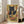 May include: Framed poster print leaning against white wall in bright living room with beige sofa. Artwork shows black cat with golden eyes using chopsticks to eat ramen noodles from decorative bowl with sushi and dumplings. Japanese-inspired illustration features warm earth tones, geometric patterns, and Asian text characters in vintage poster style.