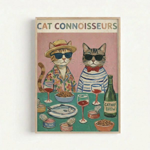 Framed illustration of two anthropomorphic cats wearing sunglasses seated at a green table with wine glasses, fish, tuna cans, and kibble bowls. Left cat wears a straw hat and floral shirt, right cat wears a striped shirt with red bow tie. Pink background with "CAT CONNOISSEURS" text at top in colorful letters. Green bottle labeled "CATNIP BREW" visible on table. Light wood frame against white wall.