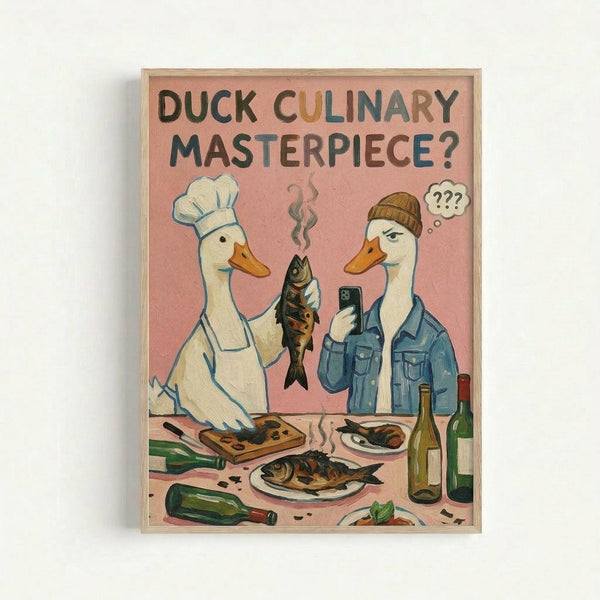 A framed poster with a pink background showing two white ducks in human clothing at a kitchen counter. The left duck wears a chef's hat and apron, holding a cooked fish. The right duck wears a beanie and denim jacket, looking confused with question marks above its head. The counter displays prepared fish dishes, wine bottles, and cooking utensils. Bold text at the top reads "DUCK CULINARY MASTERPIECE?" in green and brown letters. The artwork has a humorous cartoon style in a light wood frame.
