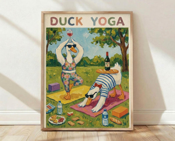 May include: Framed poster displaying two cartoon ducks doing yoga poses in a park setting. One duck balances on one leg holding a wine glass, wearing colorful floral workout clothes and sunglasses. The other duck is in downward dog pose on a pink yoga mat, wearing blue striped shirt and sunglasses with a baguette balanced on its back. Scene includes yoga blocks, wine bottle, water bottles, and snacks scattered on grass under leafy trees.