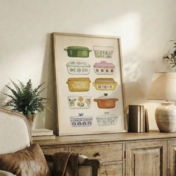 May include: Watercolor illustration of vintage casserole dishes and baking containers in various colors including green, pink, yellow, orange, and blue with floral patterns, displayed in a light wood frame on a rustic wooden sideboard alongside potted ferns, books, and ceramic vases in a cozy living room setting with warm natural lighting.