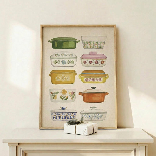 May include: Framed watercolor illustration of ten vintage casserole dishes arranged in rows, featuring various patterns and colors including green, yellow, pink, and floral designs. The artwork is displayed in a light wood frame on a cream-colored shelf next to a small wrapped gift with evergreen sprig, against a white wall.