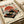 May include: Vintage-style poster print featuring a retro turntable with cherry blossom branches against a red sun and striped background, displayed on white paper with Japanese text. The design uses warm orange, teal, and cream colors in a worn, weathered aesthetic. Shown on a light wooden surface next to rolled white papers.