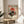 May include: Framed vintage-style Japanese poster featuring red turntable with vinyl record against sunset backdrop with cherry blossoms and mountains, displayed on round wooden side table next to beige upholstered chair with plant leaves visible in bright, minimalist room setting
