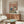 May include: Framed poster displaying cartoon ducks in yoga poses on pink background, mounted above wooden sideboard in modern living room with white curved chair, round glass coffee table, and natural lighting. The artwork shows whimsical waterfowl characters doing stretches and poses with colorful lettering at top.