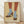 May include: Framed art print showing two legs wearing blue ribbed socks and leopard print Mary Jane shoes with block heels and ankle straps, illustrated in a vintage pop art style with warm yellow background, displayed in light wood frame leaning against white wall on wooden floor