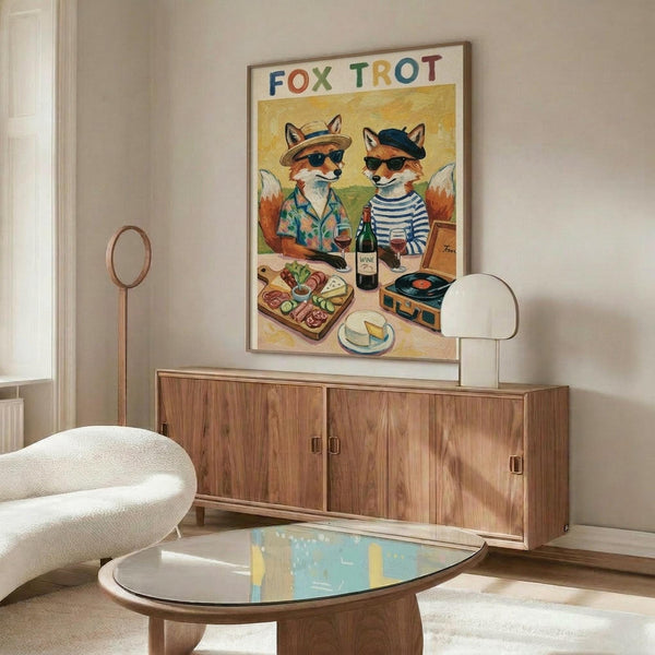 May include: Framed poster showing two anthropomorphic foxes in sunglasses sharing wine and cheese, titled "Fox Trot" in colorful letters. One fox wears a striped shirt and beret, the other a tropical shirt and hat. Scene includes charcuterie board, wine bottle, and vintage record player on yellow background. Displayed above mid-century walnut credenza in modern living room with white curved chair, brass floor lamp, oval glass coffee table, and cream walls.