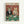 Vintage-style poster featuring two cats dressed as casino players at a green poker table. The tabby cat wears a black tuxedo with bow tie and holds a cigar, while the orange cat wears a sparkly dress and holds playing cards. Red ornate wallpaper background with poker chips, wine bottle, glass, and scattered cards on the felt table. Framed in light wood against white wall.
