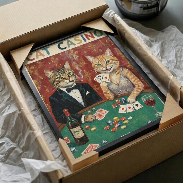 May include: Vintage-style poster showing two anthropomorphic cats in formal wear playing poker at a green felt table. One tabby cat wears a black tuxedo while an orange cat holds playing cards. The scene includes poker chips, wine bottle, and playing cards scattered on the table against a red damask wallpaper background. The framed artwork is packaged in brown cardboard with protective wrapping, showing how the print arrives to customers.