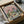 May include: Framed vintage-style poster showing two cats wearing sunglasses at a picnic, one in floral shirt holding wine glass, other in striped shirt, with cheese, grapes, bread and fish on checkered blanket under pink sky with clouds, packed in cardboard shipping box with protective wrapping