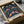 May include: Framed poster with intricate dark blue pattern featuring colorful birds, strawberries, and flowing botanical motifs in William Morris's classic Arts and Crafts style. The print sits in a cardboard shipping box with protective tissue paper, surrounded by brown paper wrapping materials on a light surface.
