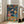 May include: Framed poster print displayed in bright living room with beige sofa and large windows. Artwork shows cartoon cat and dog in colorful space suits sharing fried chicken meal in spacecraft, with galaxy view behind them. Vibrant illustration features orange tabby cat in pink spacesuit and golden retriever in blue NASA suit, both wearing helmets, toasting with champagne glasses over table of chicken, fries, and space cola bottles.