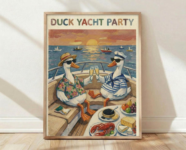 May include: Framed poster print leaning against white wall on wooden floor. Artwork shows two white ducks in sunglasses sitting on yacht deck at sunset, toasting with champagne glasses. One duck wears floral Hawaiian shirt and straw hat, other wears blue striped sailor shirt and white captain's hat. Deck features gourmet food spread including lobster, caviar, cheese, and fruit. Ocean background shows boats and orange sunset sky. Light wood frame surrounds vintage-style illustration.