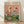 May include: Framed poster print leaning against white wall on light wood floor. Artwork shows two anthropomorphic ducks having a picnic at green table with wine glasses, bread, and food. Left duck wears floral shirt, right duck in striped shirt with red bow tie has disheveled appearance with red stains. Pink background with "DUCK PICNIC" text in colorful letters. Natural wood frame visible.