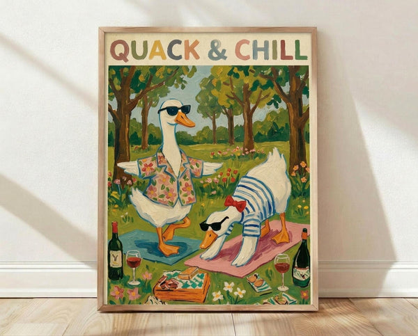 May include: Framed poster print leaning against white wall on light wooden floor. Artwork shows two white ducks wearing sunglasses in a park setting - one in floral shirt doing yoga pose on blue mat, another in striped shirt relaxing on pink blanket. Scene includes wine bottles, glasses, picnic basket, and colorful flowers scattered around green grass with trees in background. Light wood frame, vintage illustration style with warm colors.