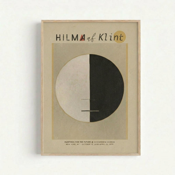 Framed exhibition poster featuring abstract geometric design with large circle split into cream and dark green halves, connected by small horizontal lines. Text reads "HILMA af Klint" at top with small red triangle and yellow circle accents. Bottom shows "PAINTINGS FOR THE FUTURE @ GUGGENHEIM MUSEUM NEW YORK, NY - OCTOBER 12, 2018-APRIL 23, 2019". Displayed in light wood frame against white wall with visible shadow.