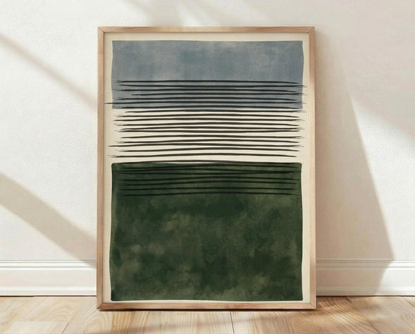 May include: Framed abstract art print leaning against white wall on light wood floor. The artwork features horizontal bands - muted blue-gray watercolor wash at top, black hand-drawn lines in middle section on cream background, and deep forest green watercolor block at bottom. Natural wood frame with white matting. Soft natural lighting creates diagonal shadows on textured white wall.