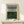 May include: Framed abstract art print with horizontal black lines transitioning from gray-blue at top to deep forest green at bottom, displayed on light wood console table against cream wall with small wrapped gift box decorated with greenery beside frame